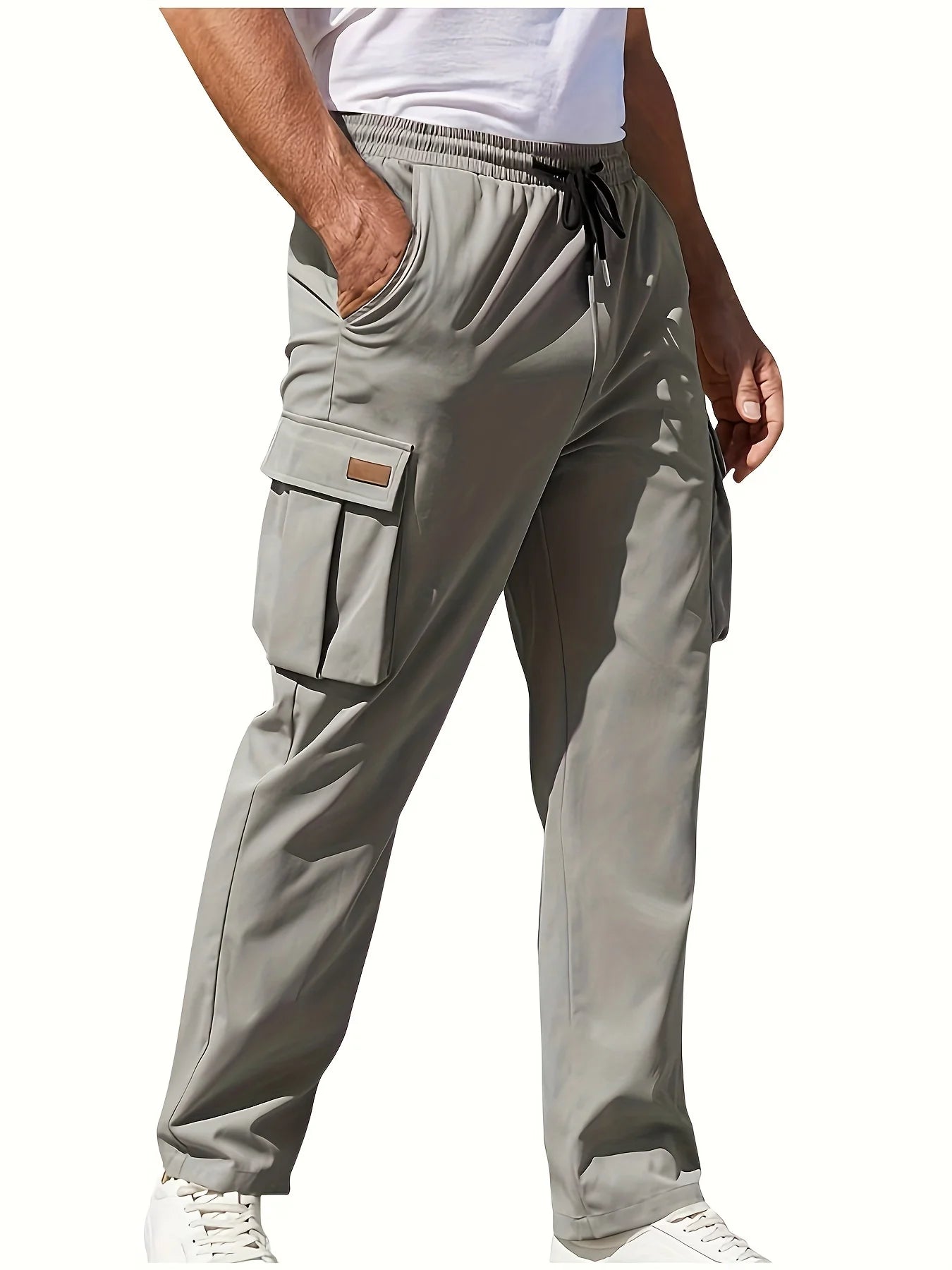 Man wearing light gray cargo pants with elastic waistband, flap side pockets, and white sneakers, styled for casual or streetwear outfits.
